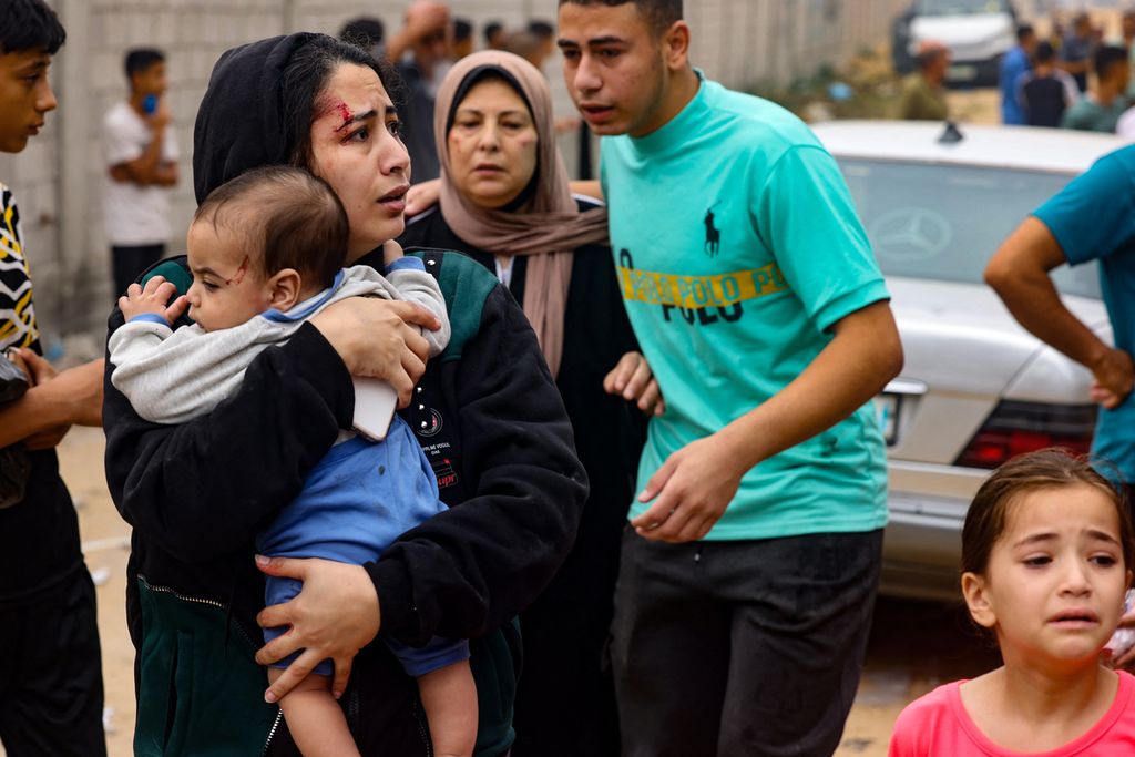 Seorang perempuan yang terluka membawa bayi setelah pengeboman yang dilakukan Israel di Rafah, di bagian selatan Jalur Gaza, Minggu (29/10/2023). 
