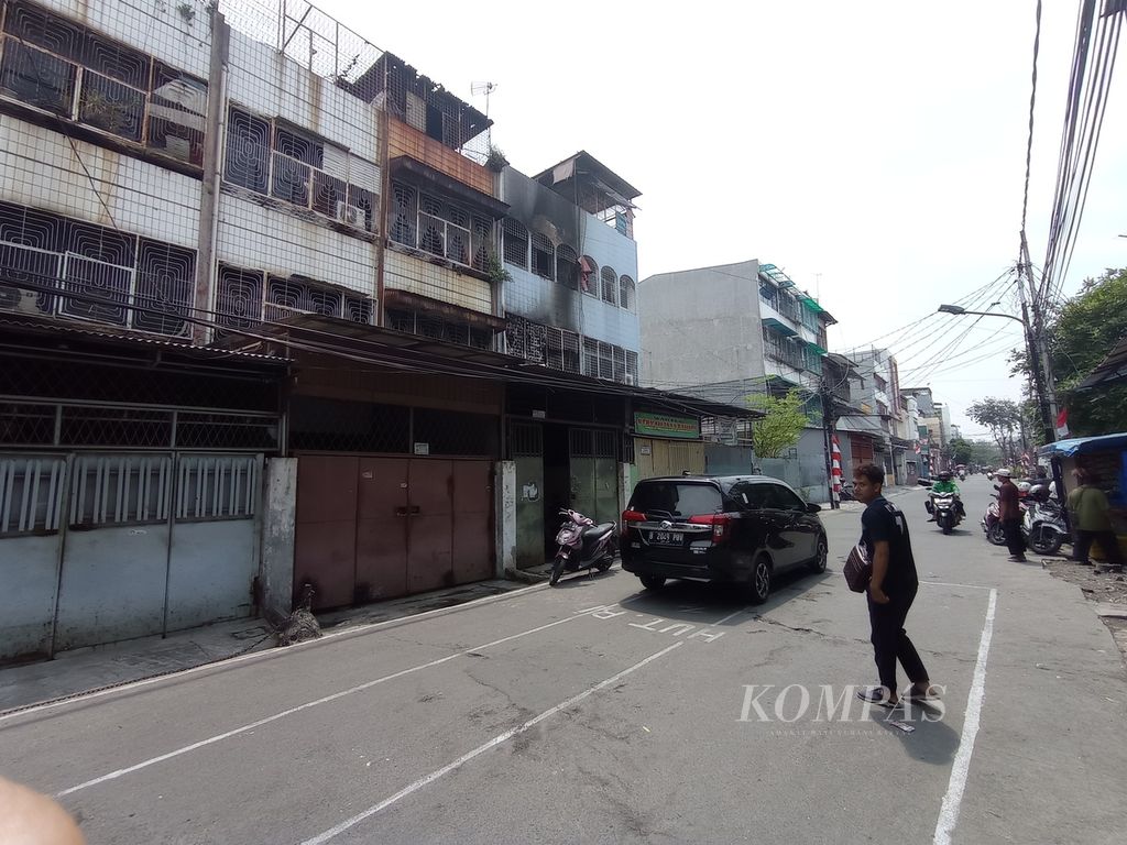 A man crosses the road in front of a shophouse building that caught fire in Duri Selatan Village, Tambora, West Jakarta, Wednesday (17/8/2022).