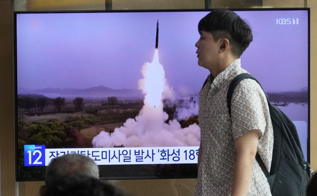 Warga Korea Selatan melintas di depan sebuah layar televisi yang menayangkan berita tentang peluncuran rudal jarak jauh oleh Korea Utara, Rabu (12/7/2023).