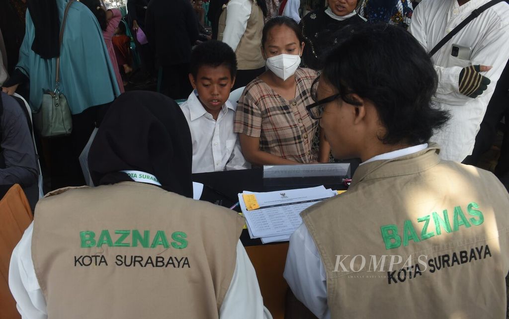 Orangtua dan anaknya mengurus administrasi pencairan dana program penebusan ijazah dan bayar tunggakan biaya sekolah di Kantor Badan Amil Zakat Nasional, Surabaya, Jumat (29/12/2023). 