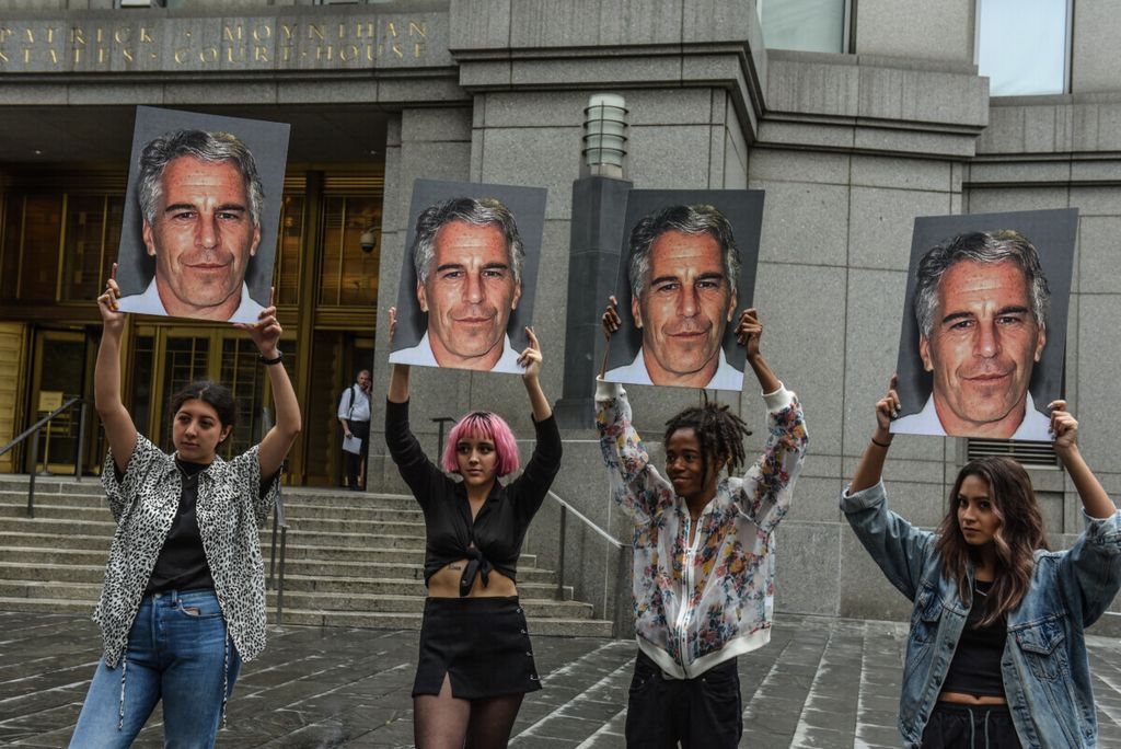 Dalam foto yang diambil pada 8 Juli 2019 ini, sebuah kelompok pengunjuk rasa yang disebut "Hot Mess" mengangkat foto Jeffrey Epstein di depan gedung pengadilan federal pada 8 Juli 2019 di New York, Amerika Serikat. Miliarder Jeffrey Epstein didakwa atas tuduhan memperdagangkan perempuan di bawah umur untuk seks.  