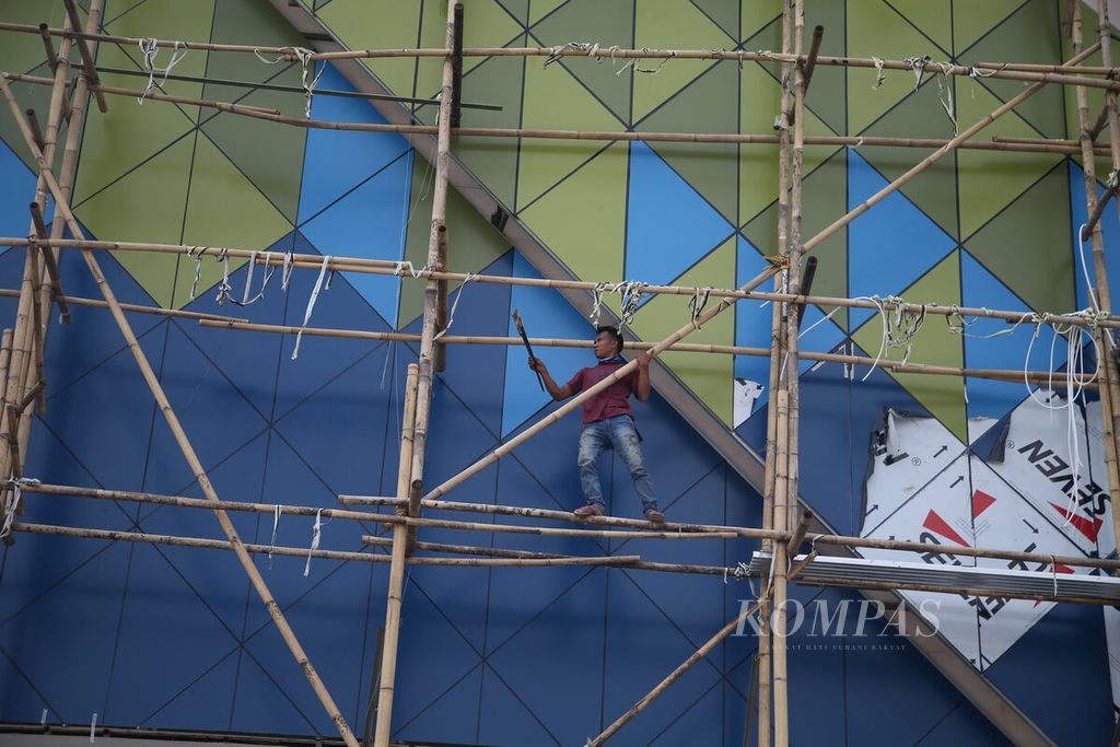 Dengan kondisi alat keselamatan kerja yang minim, para buruh bangunan bergelantungan pada tiang penyangga (steger) dari bambu untuk pengecatan dinding sebuah pusat perbelanjaan baru di kawasan Pamulang, Tangerang Selatan, Banten Kamis (14/5/2020).  