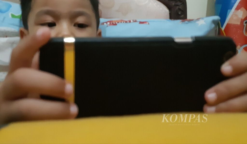 Seorang anak bermain gawai milik orangtuanya, Sabtu (20/4/2019). Orangtua perlu memberikan literasi digital dari sejak usia dini kepada anak-anak, terutama di era digital. 