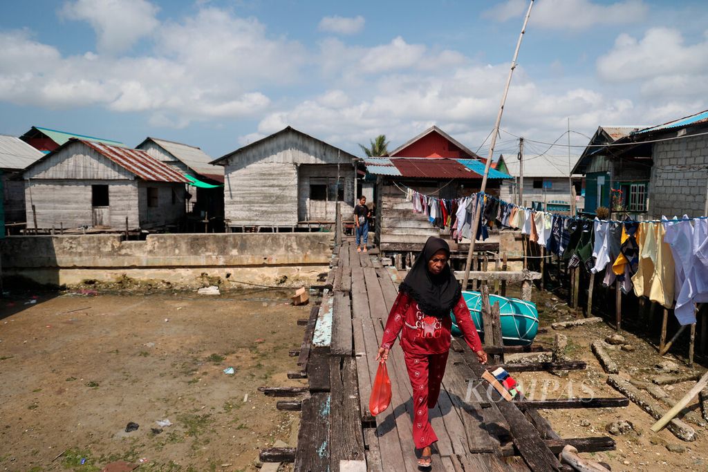 Warga melintasi jembatan kayu yang menghubungkan antarrumah di Kampung Nelayan Siwalima, Kecamatan Pulau-pulau Aru, Kabupaten Kepulauan Aru, Maluku, Kamis (21/9/2023).
