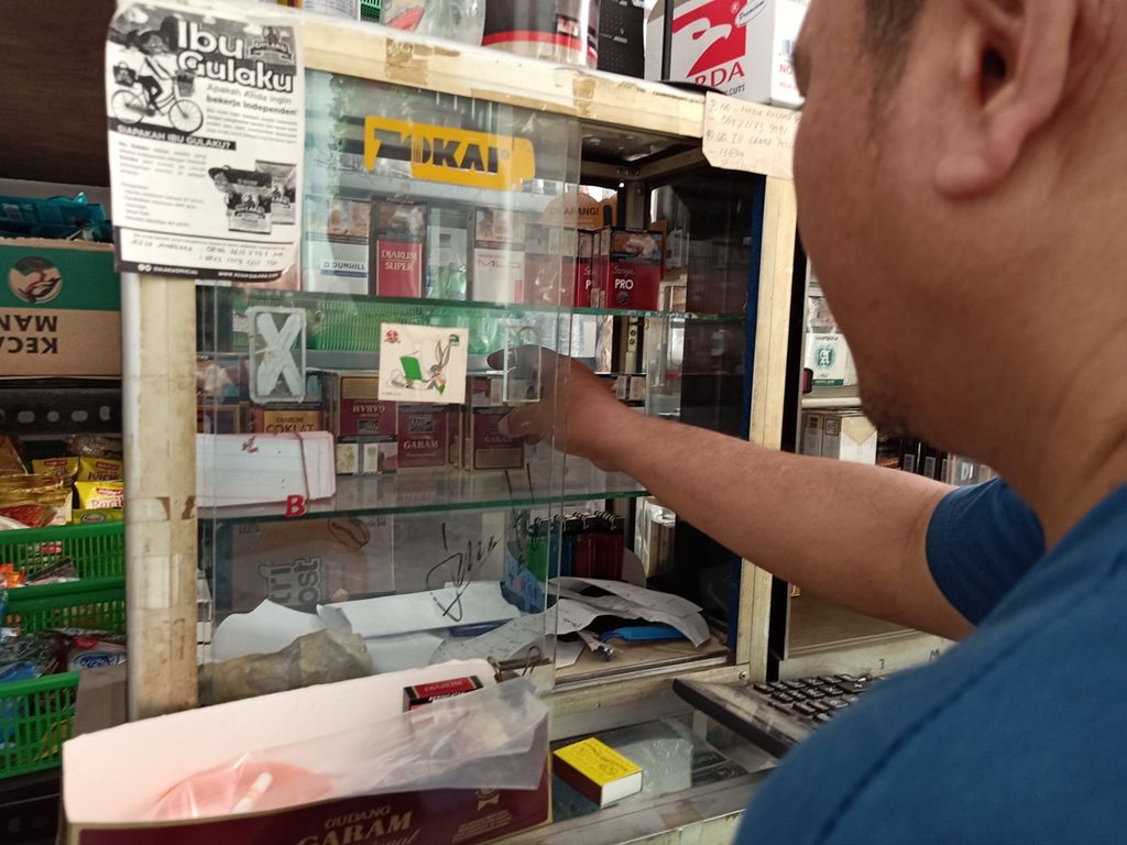 Anto (50), pedagang rokok, sedang menata dan menyusun dagangannya untuk menarik konsumen. 