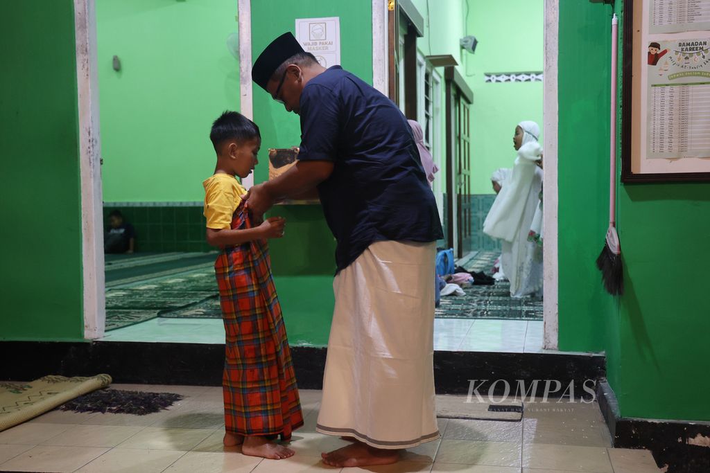 Seorang anak ditemani ayahnya saat hendak menunaikan shalat di Dusun Ngaran, Desa Margokaton, Seyegan, Sleman, DI Yogyakarta, Kamis (20/4/2023). 