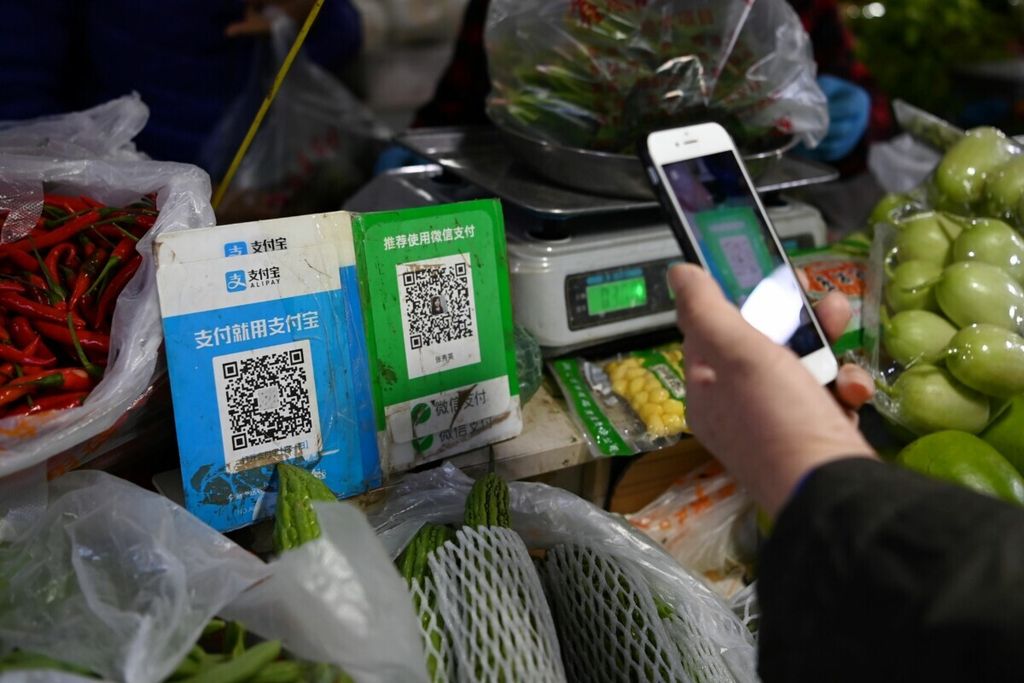 Pelanggan melakukan pembayaran menggunakan kode pembayaran WeChat dengan ponsel pintarnya, di sebelahnya adalah kode pembayaran Alipay, di pasar tradisional Beijing pada 3 November 2020. 
