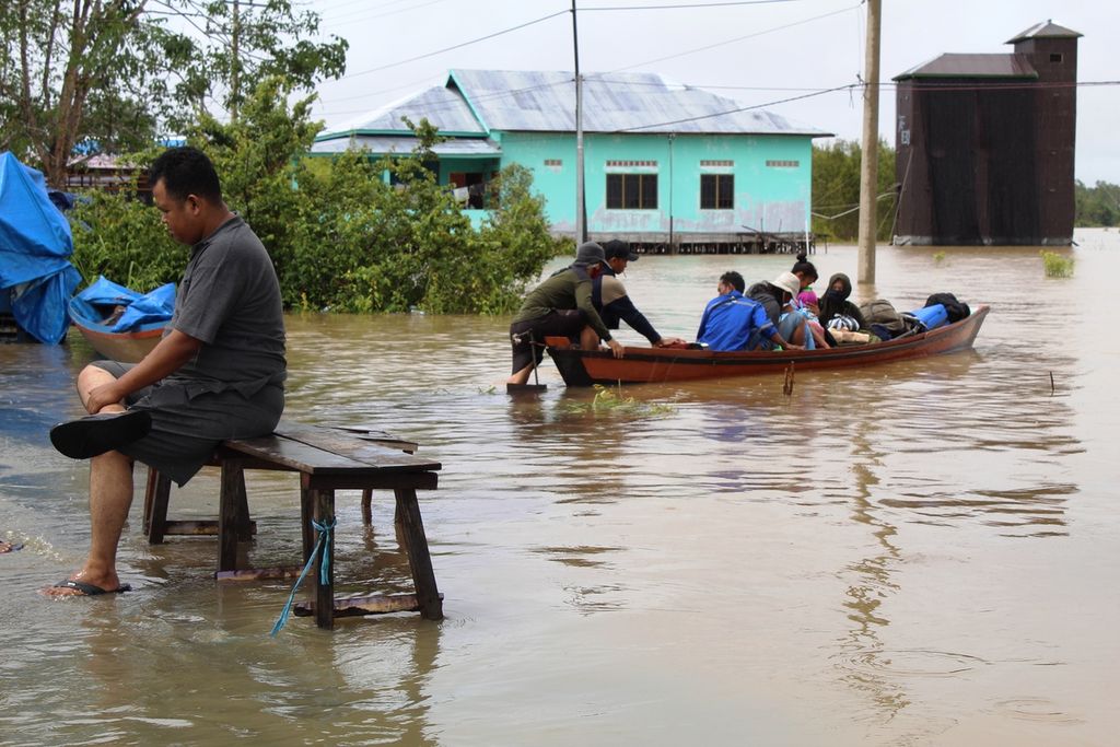 Warga Desa Penda Barania menggunakan perahu kayu bermotor untuk melintasi banjir di Bukit Rawi, Kabupaten Pulang Pisau, Kalteng, Minggu (14/11/2021). Banjir setiap tahun merendam wilayah jalur Trans-Kalimantan tersebut.