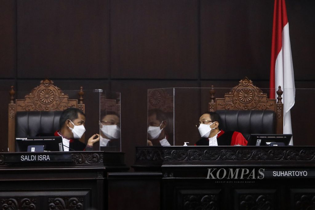 Hakim konstitusi Saldi Isra (kiri) berbincang dengan hakim konstitusi Suhartoyo saat pembacaan keputusan terkait perkara perselisihan sengketa pemilihan kepala daerah tahun 2020 di Gedung Mahkamah Konstitusi, Jakarta, Senin (15/02/2021). 
