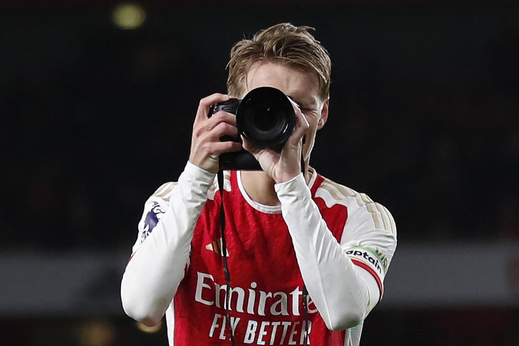 Gelandang Arsenal Martin Odegaard memegang sebuah kamera dan memotret saat melakukan selebrasi seusai pertandingan Liga Inggris antara Arsenal dan Liverpool di Stadion Emirates, London, Minggu (4/2/2024). 