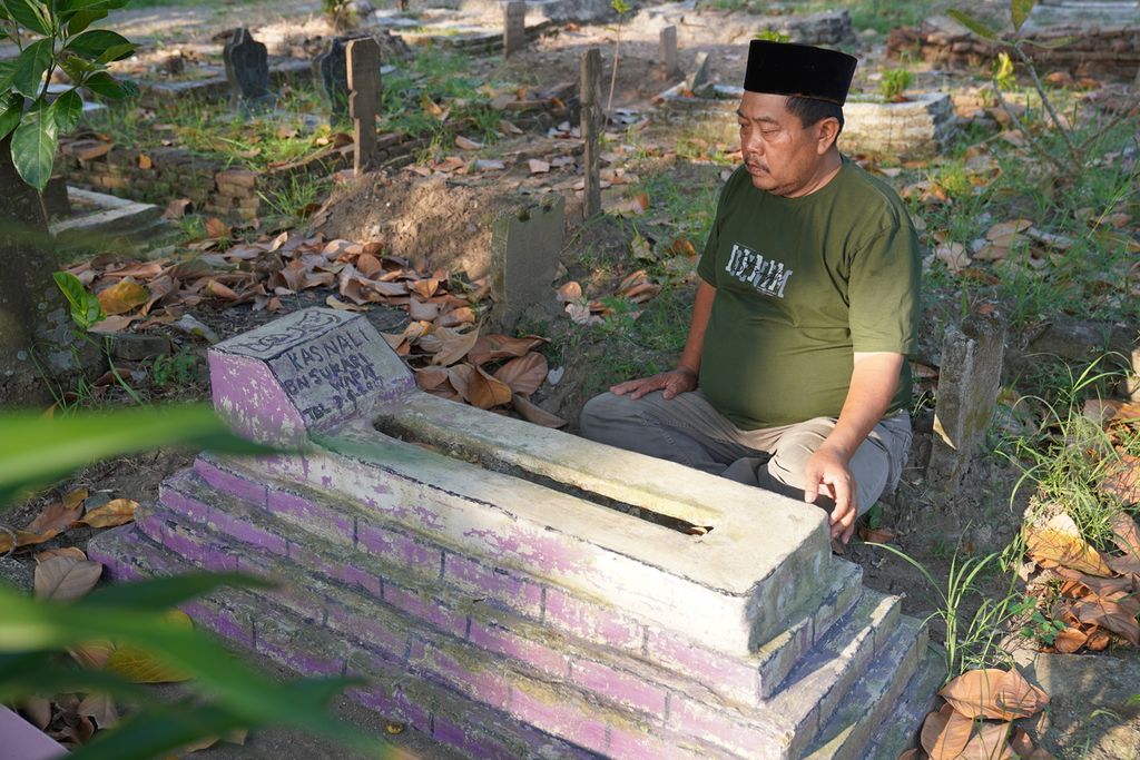 Sukari Tamin (53), sedang berziarah ke makam anaknya, Kasnali, di tempat pemakaman umum Banasari, Desa Gembongan, Kecamatan Babakan, Kabupaten Cirebon, Jawa Barat, Sabtu (22/7/2023). Kasnali merupakan anak buah kapal perikanan migran yang meninggal di Cile pada 2017 silam.