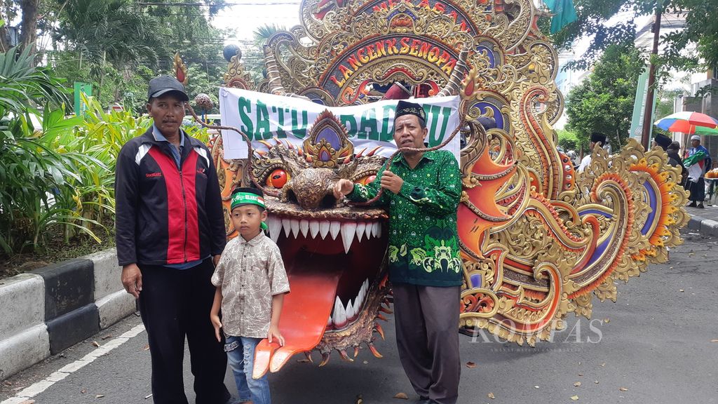 Ari (kanan), seorang guru asal Yayasan Al Masyitoh, Surabaya, dengan sukacita berkenalan dengan peserta dan penonton acara karnaval Seabad NU, Selasa (7/2/2023), di Alun-alun Sidoarjo. Ia menganggap bahwa momen tersebut sekaligus sebagai caranya bersilaturahmi dengan orang lain.