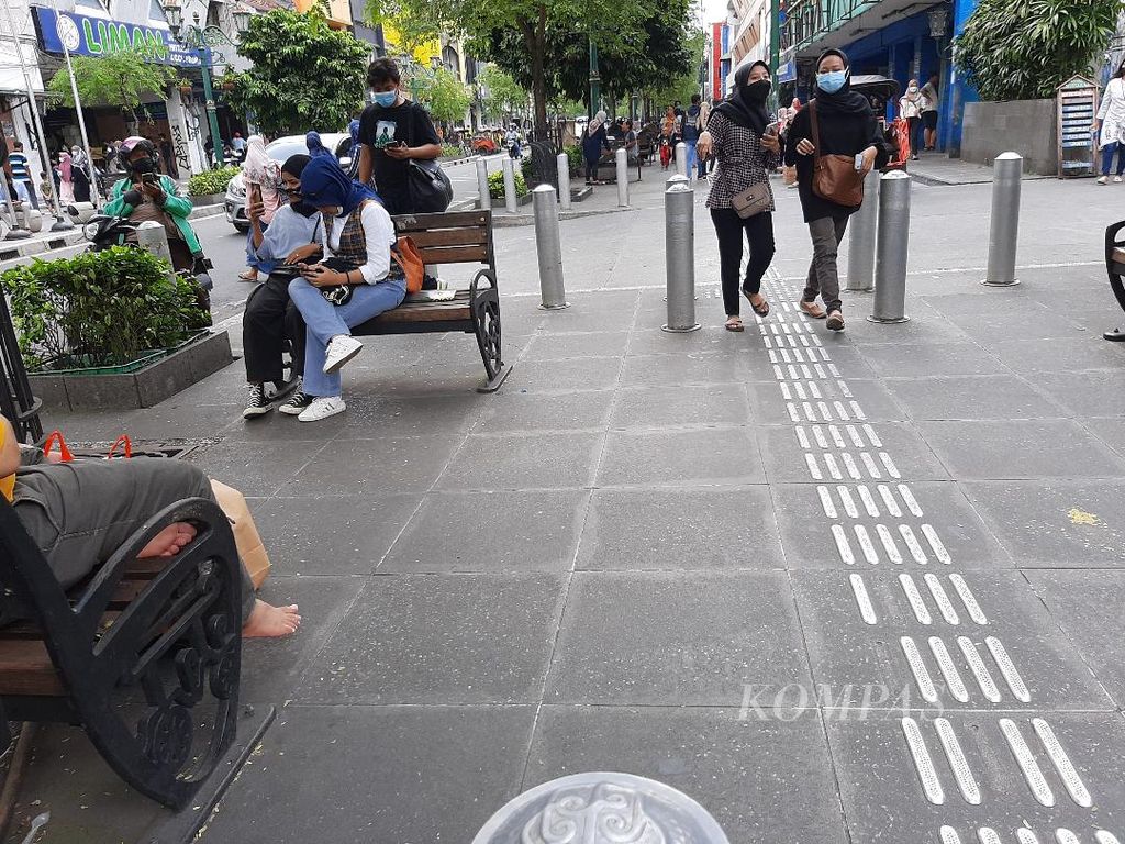 Visitors are seen sitting and some other tourists walking along the sidewalks of Malioboro. The arrangement and relocation of street vendors, which was carried out last February, made the sidewalks look clean and tidy..