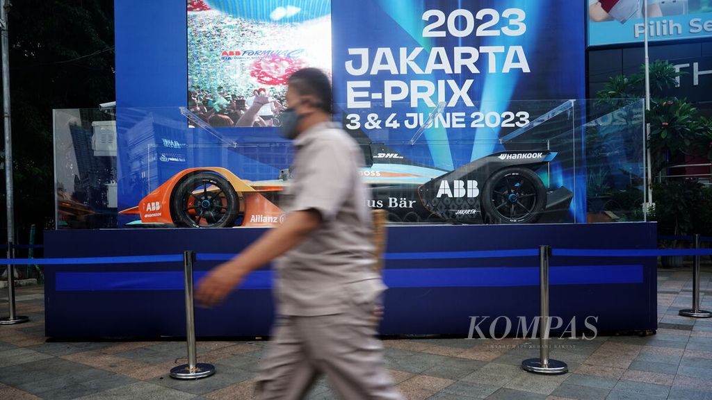 Warga melintasi sebuah replika mobil balap Formula E yang dipajang di salah satu sudut kawasan Bundaran Hotel Indonesia, Jakarta, Senin (27/3/2023). 