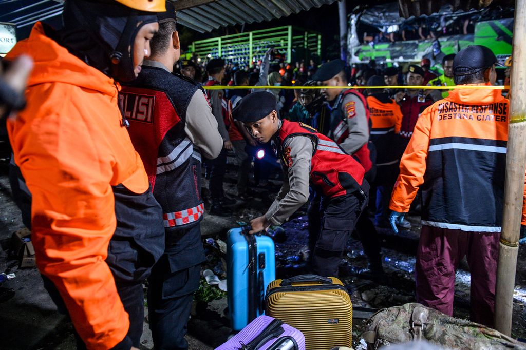 Petugas kepolisian mengumpulkan barang milik korban kecelakaan bus pariwisata di Desa Palasari, Kecamatan Ciater, Kabupaten Subang, Jawa Barat, Sabtu (11/5/2024).