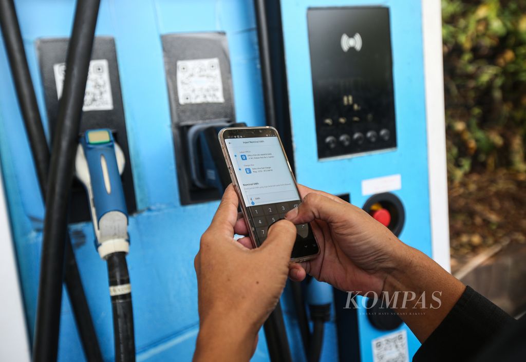 Warga menggunakan aplikasi untuk menambah daya pada mobilnya di stasiun pengisian kendaraan listrik umum (SPKLU) di kantor PLN di kawasan Gambir, Jakarta Pusat, Senin (18/12/2023). 
