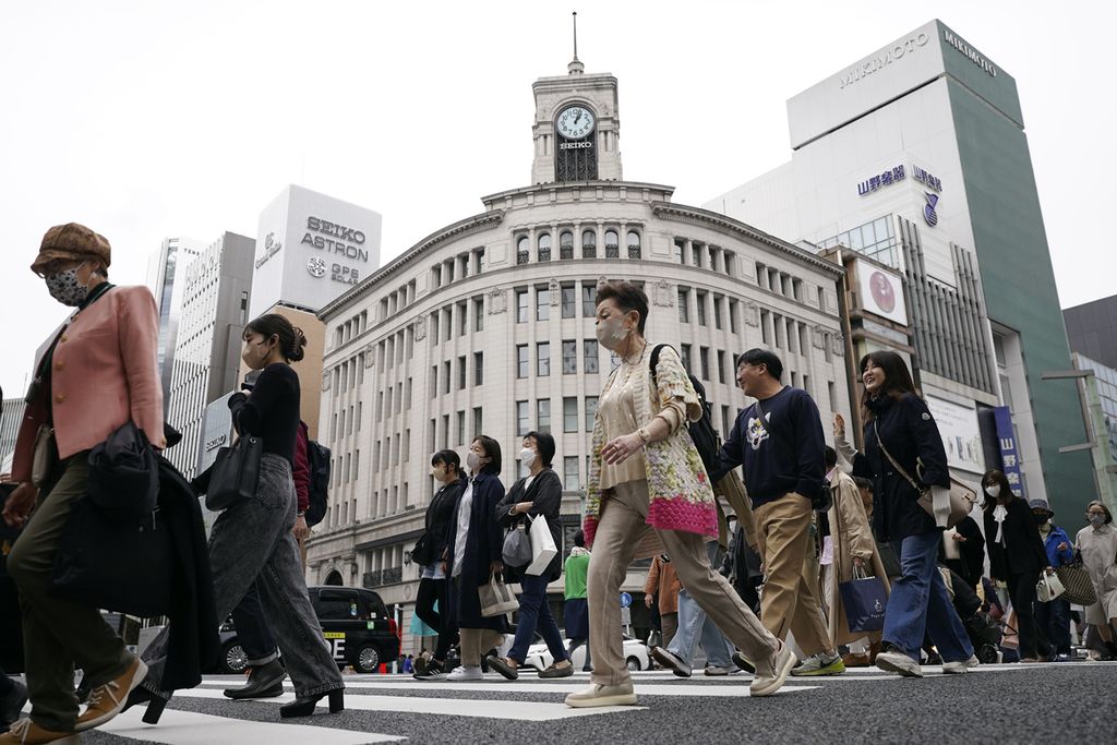 Orang-orang berjalan melintasi penyeberangan pejalan kaki di distrik perbelanjaan Ginza, Tokyo, pada 31 Maret 2023. 