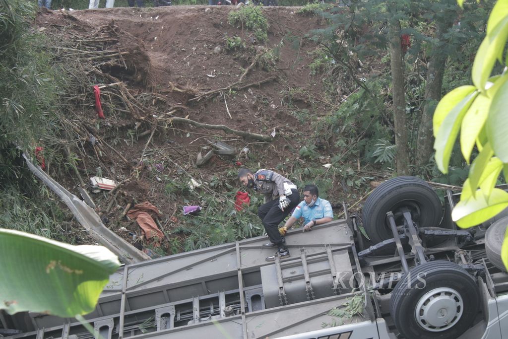 Petugas memeriksa bangkai bus yang mengalami kecelakaan maut di Tanjakan Cae, Desa Sukajadi, Kecamatan Wado, Sumedang, Jawa Barat, Kamis (11/3/2021). Kondisi jalan yang sempit dianggap tidak layak dilalui oleh bus bermuatan lebih dari 60 orang.