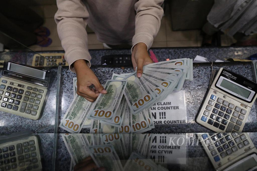 Pegawai perusahaan penukaran uang asing, Valuta Artha Mas, di ITC Kuningan, Jakarta, 29 Juni 2022, menghitung dan memeriksa kondisi lembaran uang dollar Amerika Serikat. 