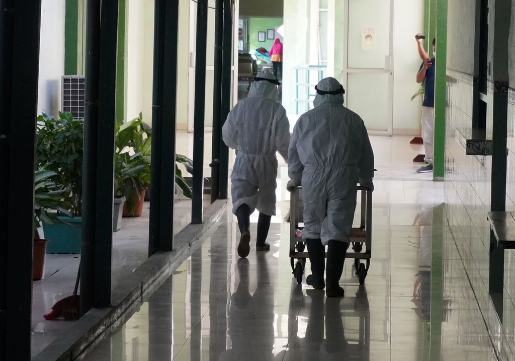 Petugas pemulasaraan jenazah Rumah Sakit Umum Daerah Kardinah Kota Tegal, Jawa Tengah membawa jenazah pasien Covid-19 melewati lorong rumah sakit, Rabu (30/6/2021). 