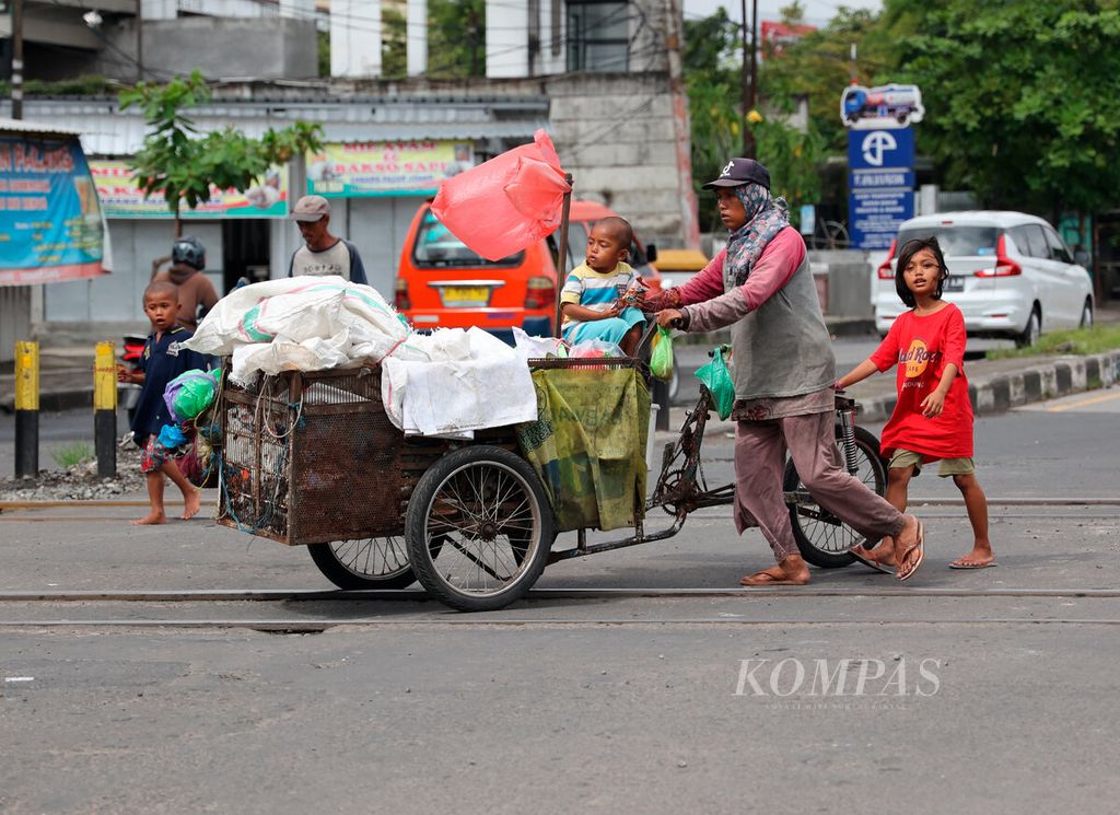 Satu keluarga berjalan beriringan dengan gerobaknya saat mereka memulung sampah yang dapat dijual, di Jalan Kaligawe, Kota Semarang, Jawa Tengah, Rabu (22/2/2022). Minimnya akses ekonomi, kesehatan, hingga pendidikan menyebabkan kemiskinan terus mengakar pada kelompok warga miskin ekstrem.