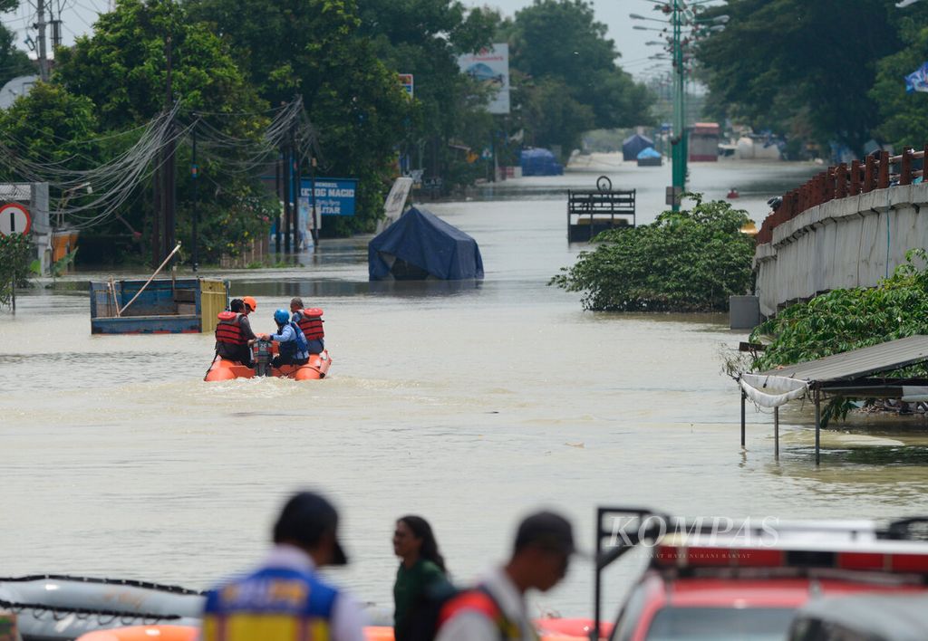 Officials use a rubber boat to travel across the flooded Demak-Kudus north coast route in Karanganyar District, Demak Regency, Central Java on Monday (12/2/2024).