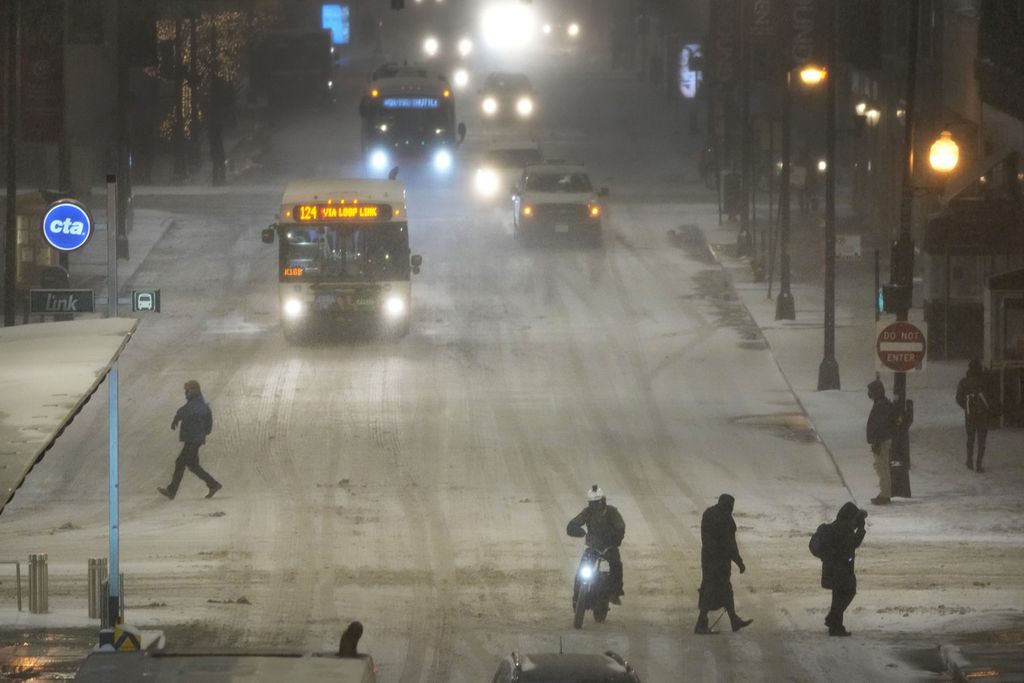 Para pejalan kaki berjalan di jalanan yang tertutup salju di Chicago, Kamis (22/12/2022). 