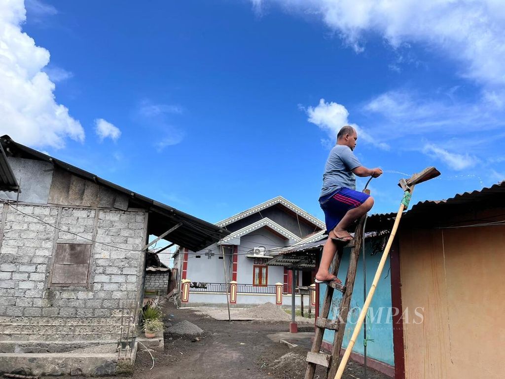 Seorang warga menyemprotkan air untuk membersihkan abu vulkanik imbas erupsi Gunung Ruang, Tagulandang, Kabupaten Sitaro, Sulawesi Utara, Kamis (9/5/2024).