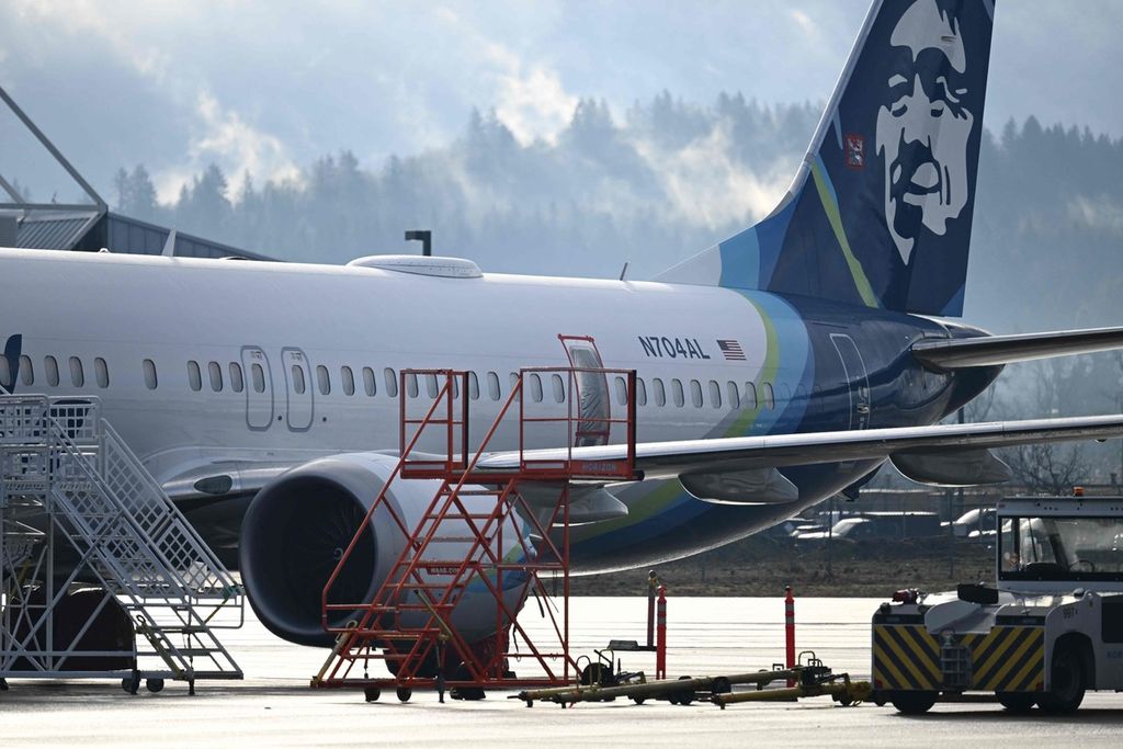 Boeing 737 Max 9 dengan nomor N704A yang mengalami insiden tengah diparkir di hanggar perbaikan di Bandara Internasional Portland pada Jumat (5/1/2024). <i>Frame</i> pintu darurat yang terlepas tampak ditutup dengan plastik.