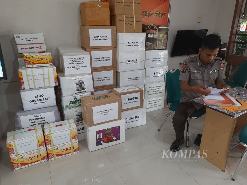 Petugas satpam BPBD Sumatera Barat memeriksa catatan bantuan rendang yang masuk untuk korban gempa M 5,6 Cianjur di kantor badan tersebut, Padang, Sumbar, Rabu (23/11/2022) siang. Pemerintah Provinsi Sumbar melalui BPBD provinsi menghimpun bantuan rendang dari berbagai kalangan pada 22-24 November 2022.