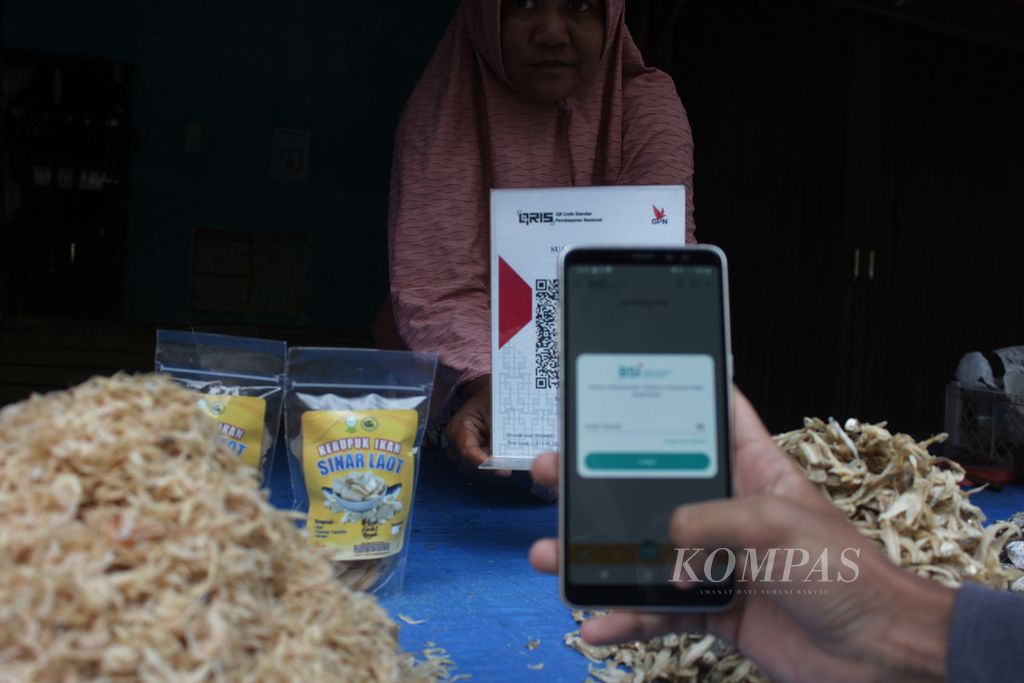 Pembeli melakukan pindai kode batang untuk membayar saat membeli produk usaha mikro, kecil, dan menengah (UMKM) di sentra penjualan ikan asin di Kecamatan Leupung, Kabupaten Aceh Besar, Aceh, (21/6/2022). Pelaku usaha warga pesisir di Aceh Besar mulai menerapkan sistem digitalisasi agar memudahkan transaksi dan penjualan.