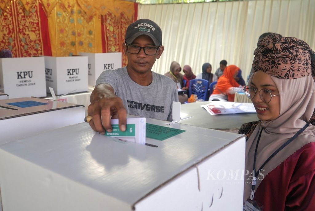 Petugas berpakaian adat Minangkabau membantu pemilih memasukkan surat suara ke dalam kotak di TPS 04 di Kelurahan Gurun Laweh, Kecamatan Nanggalo, Kota Padang, Rabu (14/2/2024). 