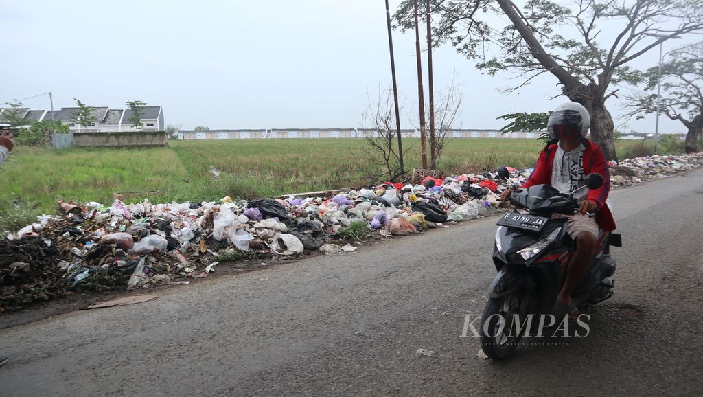 Warga melintasi tumpukan sampah di Jalan Nyi Mas Gandasari, Desa Junjang, Kecamatan Arjawinangun, Kabupaten Cirebon, Jawa Barat, Selasa (11/10/2022). Sampah itu tidak hanya mengganggu pengendara jalan, tetapi juga menyebar ke lahan pertanian.