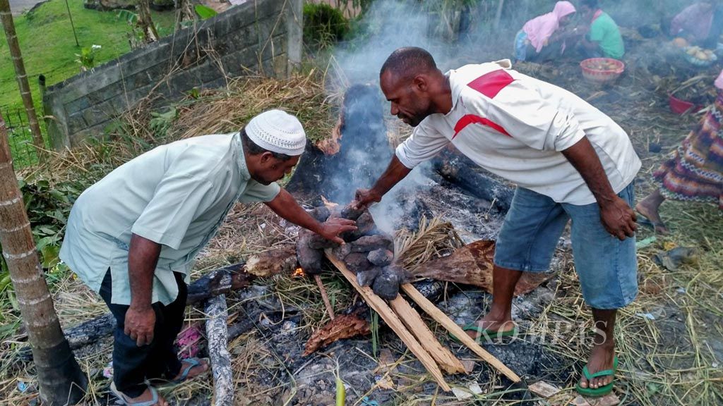 Ketua Komunitas Muslim Wamena Hadiman Asso (kiri) bersama salah satu perwakilan pemuda gereja bahu-membahu dalam acara bakar batu untuk menyambut datangnya   Ramadhan di daerah Angkasa, Kota Jayapura, pada 26 Mei 2017 lalu.
