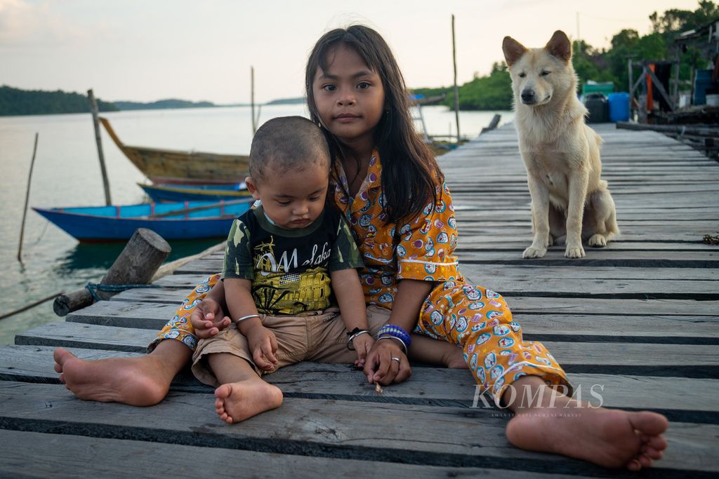 Anak suku Laut, Nia (9) dan Yobel (1), bermain bersama anjing mereka di Kampung Air Bingkai, Desa Tajur Biru, Kecamatan Temiang Pesisir, Kabupaten Lingga, Kepulauan Riau, Senin (18/7/2022).