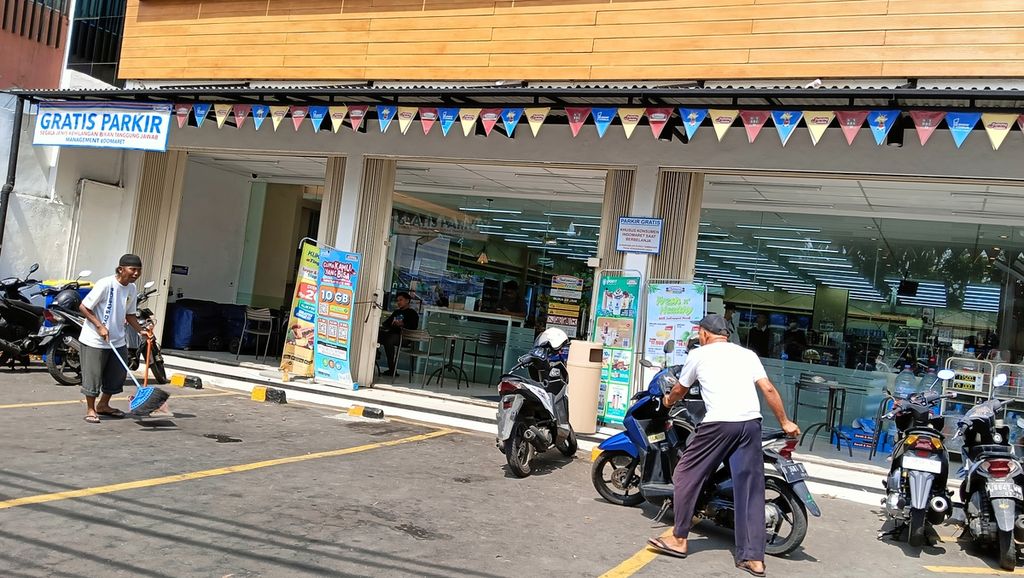 Soleh (54), juru parkir di minimarket di Kelapa Dua, Kebon Jeruk, Jakarta Barat, Sabtu (23/10/2023) siang, sedang merapikan kendaraan pelanggan. Meski di minimarket itu tertulis parkir gratis, Soleh dan temannya tetap bertahan.