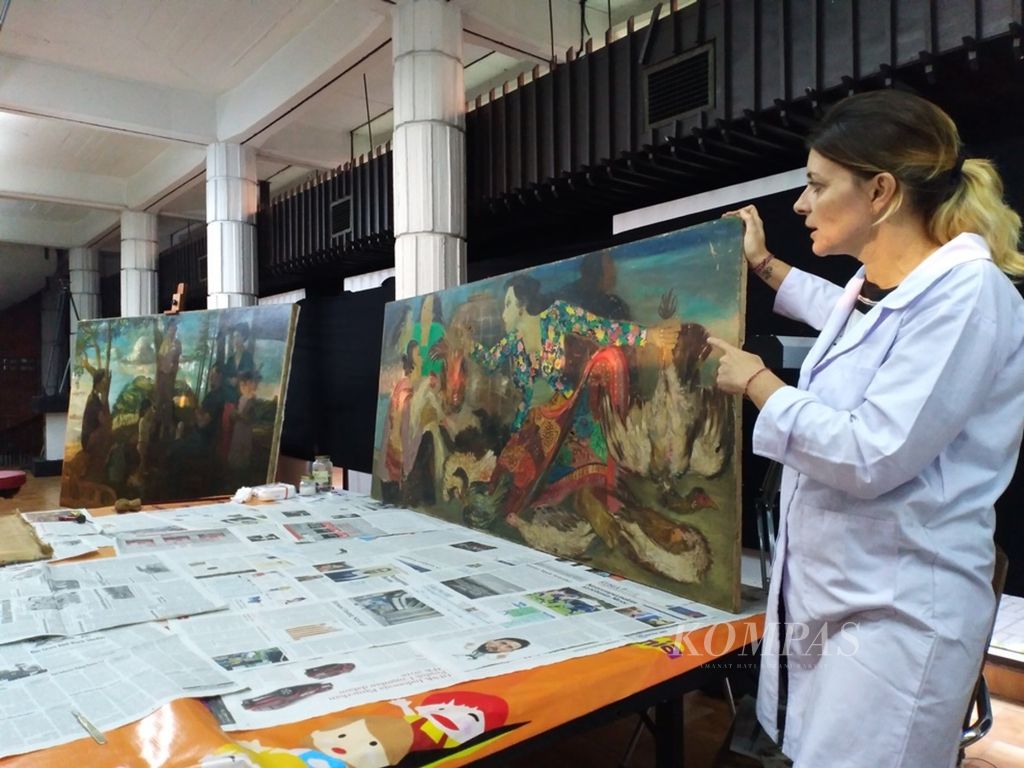 Michaela Anselmini menunjukkan dua lukisan karya S Sudjojono (sebelah kiri) dan lukisan Hendra Gunawan (sisi kanan) saat melakukan restorasi dan perawatan di Bentara Budaya Jakarta, Rabu (6/6/2018).