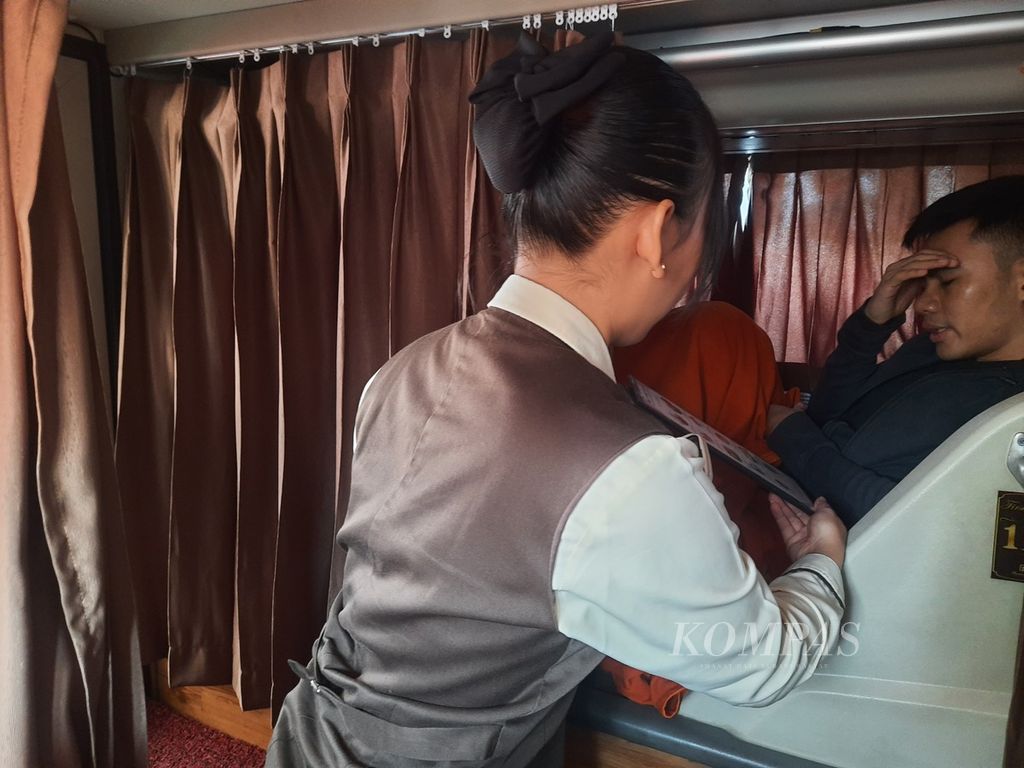 Pramugari Perusahaan Otobus (PO) Rosalia Indah sedang menawarkan menu makanan pada penumpang <i>sleeper</i><i>bus</i> yang akan disajikan di Subang, Jawa Barat, Senin (1/4/2024). 