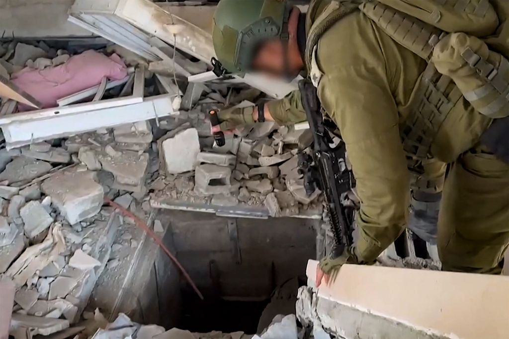 Tangkapan layar yang diambil dari rekaman selebaran yang dirilis tentara Israel pada 3 November 2023 ini menunjukkan seorang tentara Israel memeriksa pintu masuk terowongan yang digunakan Hamas di Jalur Gaza.
