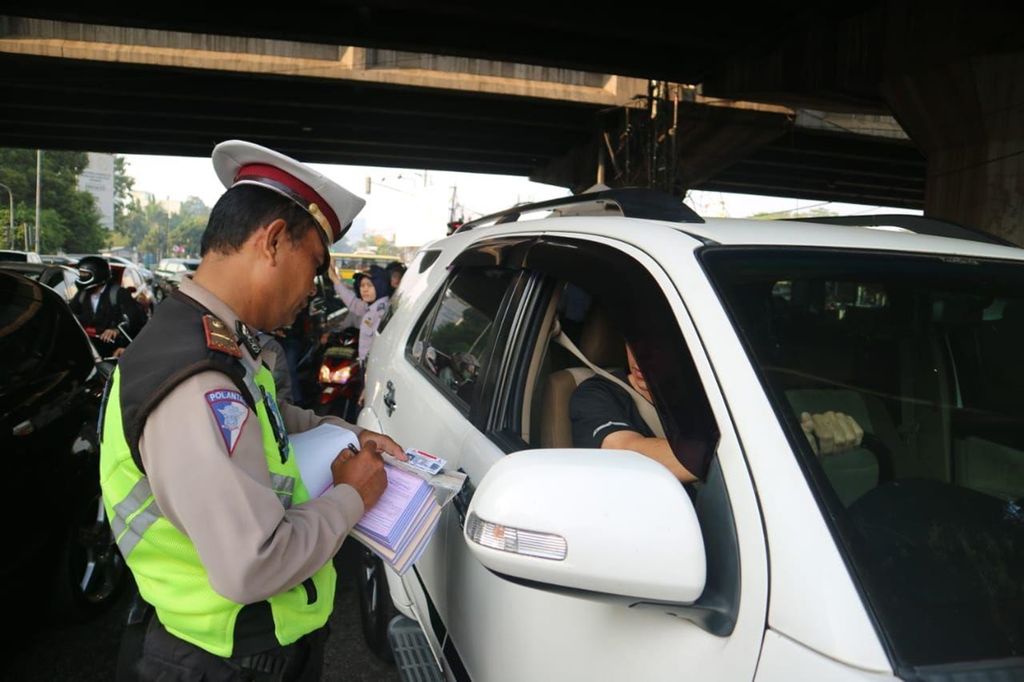 Polisi lalu lintas memberikan sanksi tilang kepada pengguna mobil pribadi yang melanggar aturan ganjil-genap di Jalan Raya Fatmawati, Jakarta Selatan, Senin (9/9/2019).