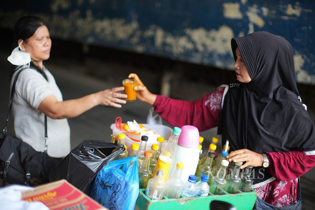 Ibu Tati (48) asal Solo melayani pembeli jamu di Pasar Perumnas Klender, Jakarta Timur, Selasa (12/12/2023).