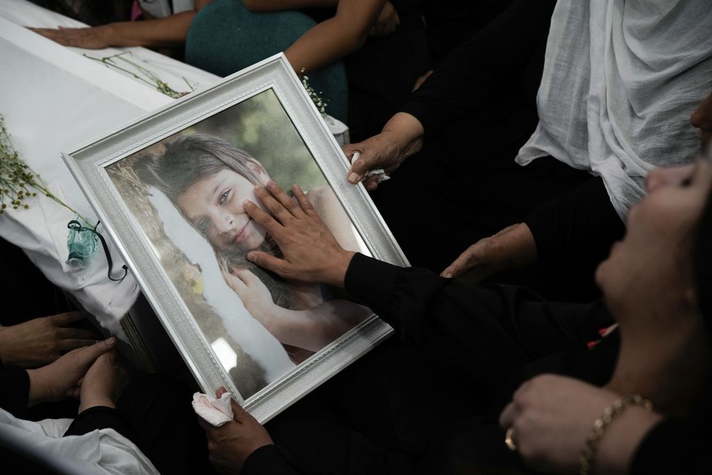 Para anggota komunitas Druze menempatkan foto Alma Fkhrden (12) di peti jenazahnya dalam upacara pemakamannya di Desa Majdal Shams, wilayah pendudukan Dataran Tinggi Golan, MInggu (28/7/2024). 