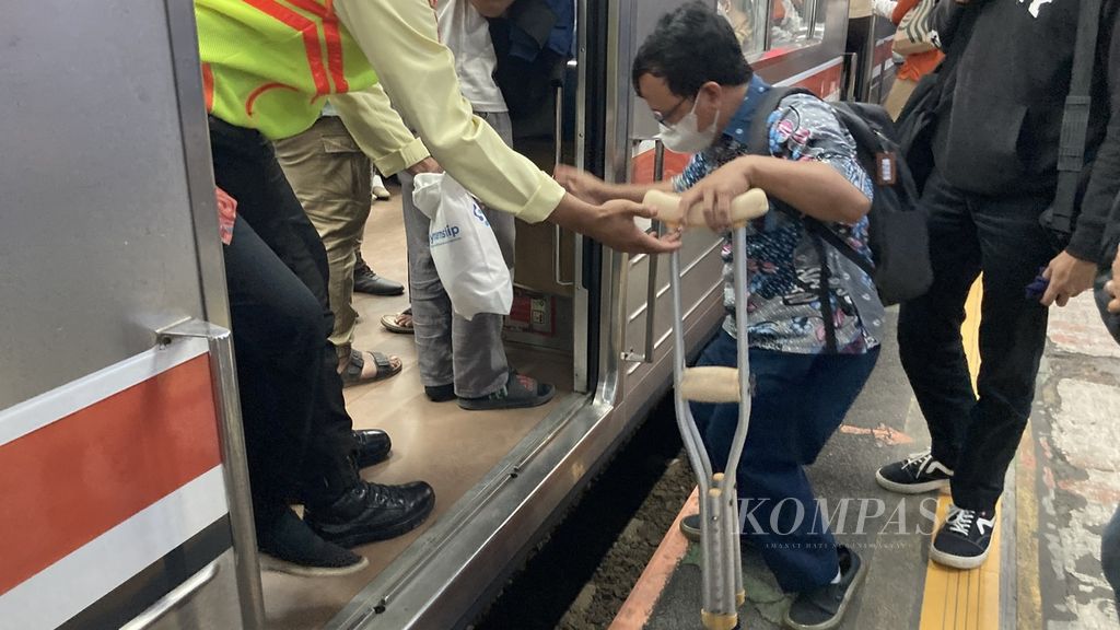 Penyandang disabilitas dibantu petugas stasiun untuk mengakses kereta rel listrik (KRL) di Stasiun Cawang, Jakarta pada Jumat (26/5/2023). Celah antara peron dan gerbong kereta kerap jadi perhatian penyandang disabilitas karena menyulitkan mereka untuk naik kereta, serta dapat membahayakan mereka.