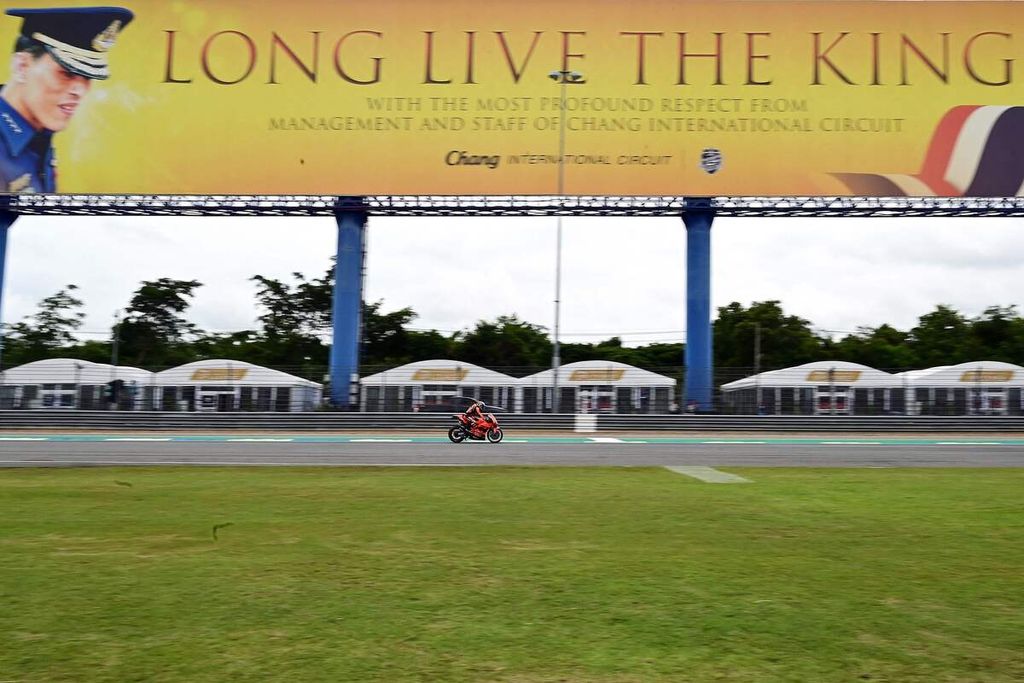Pebalap Tech3 KTM Factory Racing Raul Fernandez mengendari motornya melewati papan reklame bergambar wajah Raja Thailand Maha Vajiralongkorn saat sesi latihan bebas pertama MotoGP seri Thailand di Sirkuit Internasional Chang, Buriram, Jumat (30/9/2022). 
