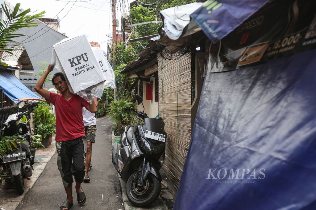 Dua petugas membawa logistik Pemilu 2024 di RW 8 Kelurahan Petamburan, Kecamatan Tanah Abang, Jakarta Pusat, Selasa (13/2/2024).
