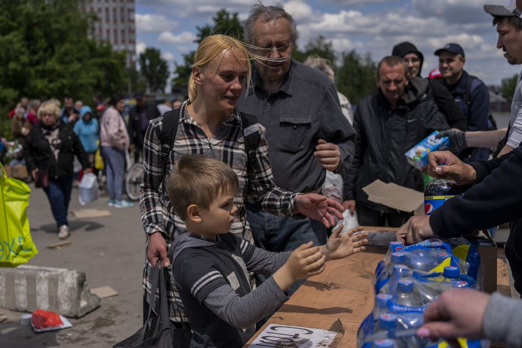 Sejumlah pengungsi Ukraina, termasuk anak-anak, mengantre untuk mendapatkan jatah makanan di sebuah lokasi di Kharkiv, Ukraina (19/5/2022). Invasi Rusia membawa derita bagi warga Ukraina dan memengaruhi cara pandang mereka tentang nasonalisme yang kian menguat untuk melawan Rusia.