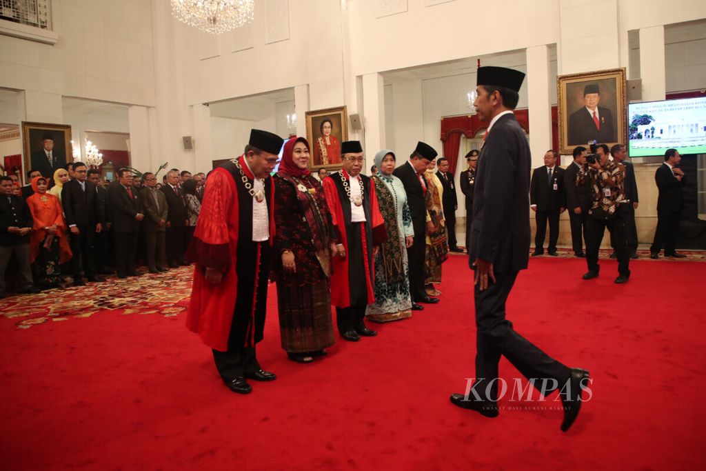 Presiden Joko Widodo memberikan ucapan selamat kepada hakim konstitusi Aswanto dan Wahiduddin Adams seusai mengucapkan di Istana Negara, Jakarta, Kamis (21/3/2019). Aswanto dan Wahiduddin Adams kembali menjabat sebagai hakim konstitusi periode 2019-2024. 