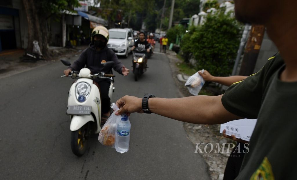 Warga membagikan takjil kepada pengendara sepeda motor yang melintas menjelang waktu berbuka puasa di kawasan Kembangan, Jakarta Barat, Selasa (28/3/2023). 