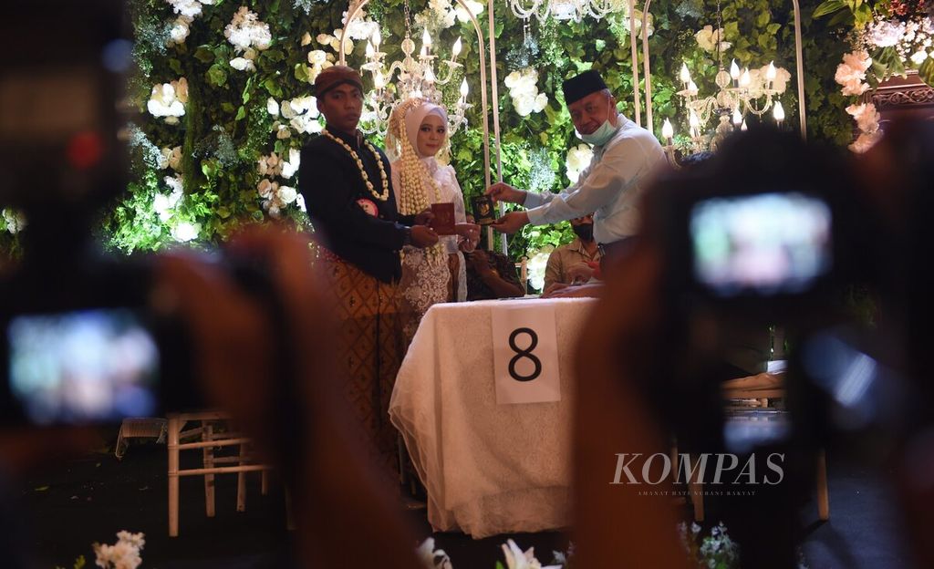 Pasangan pengantin berfoto seusai resmi menikah saat sidang isbat nikah massal di Empire Palace, Kota Surabaya, Jawa Timur, Selasa (30/8/2022). Sebanyak 120 pasangan mengikuti kegiataan yang digelar oleh Pemkot Surabaya dengan Pengadilan Agama. 