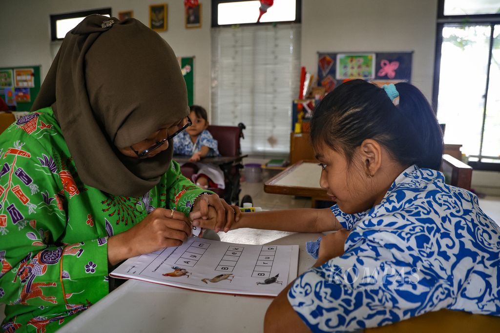 Guru mendampingi anak dengan disabilitas belajar di Sekolah Luar Biasa Yayasan Pembinaan Anak Cacat Jakarta, Kamis (18/1/2024).  